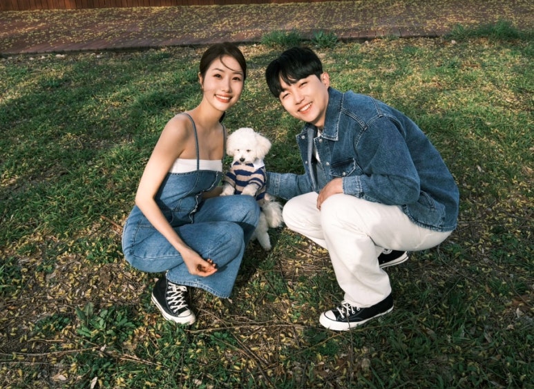 한강 풀밭에 쪼그려 앉아 강아지와 함께 웃는 청청 커플 컷이에요.