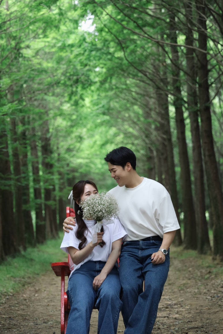 흰 티와 청바지에 베일을 쓰고 안개꽃 부케로 얼굴을 살짝 가린 삼각대 셀프 컷이에요.