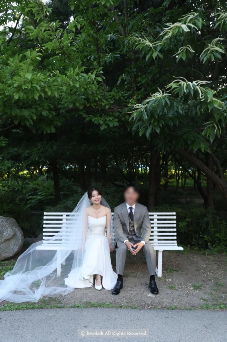흰 벤치에 베일을 길게 늘어뜨리고 앉은 컷