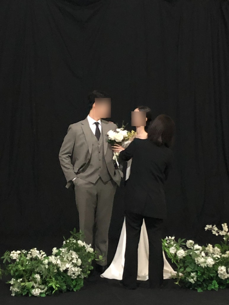 검정 배경 앞에서 헬퍼가 매무새를 정리해 주는 모습