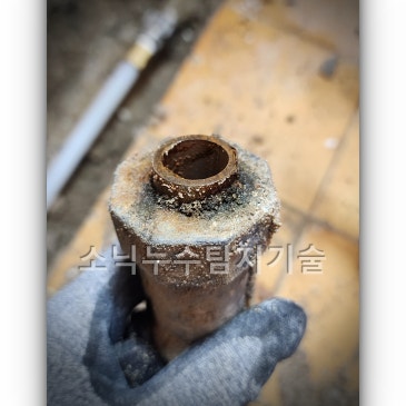 잘라낸 강관 끝부분, 이음쇠가 남아 있는 안쪽에 부식과 이물질이 두껍게 붙어 있는 상태