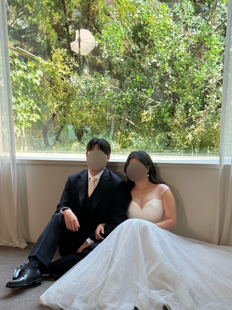 통창 앞 바닥에 앉은 커플, 창밖이 초록으로 가득