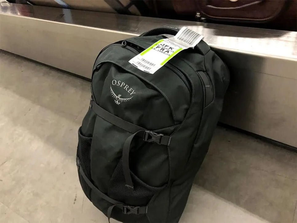 공항 터미널에서 항공기 알림을 확인하며 위탁 수하물을 대기하는 여행객들