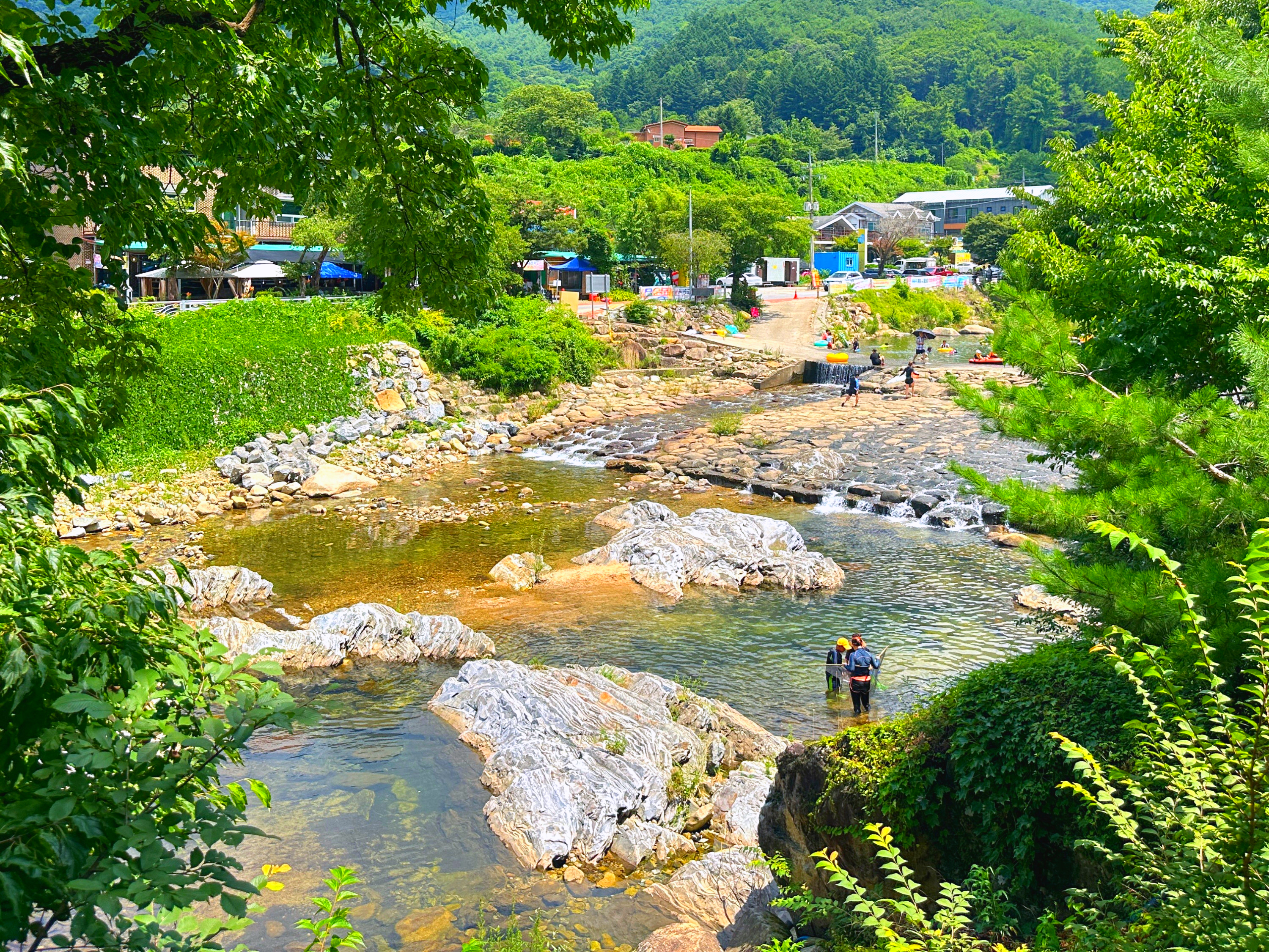 People wading in the clear, waist-deep waters of Songgye Valley