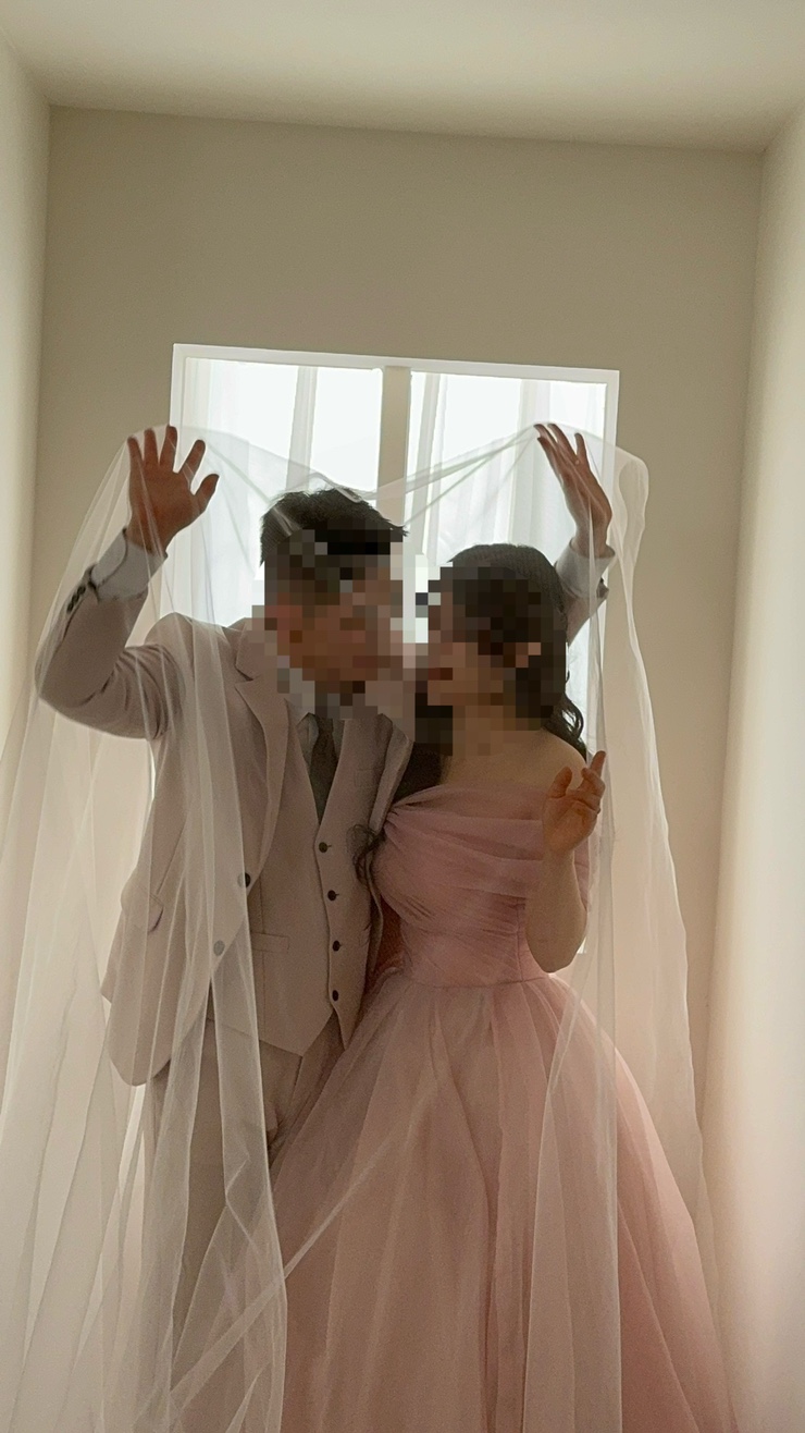 흰 벽 속 작은 창 앞에서 베일을 쓴 커플