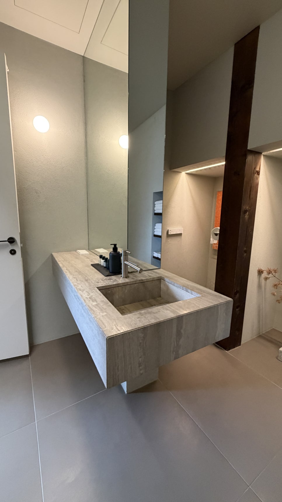 오래된 기둥 곁에 분명한 표정으로 삽입된 세면·샤워·욕조 공간. 물을 다루는 성능은 현대적으로, 집의 뼈대는 보이게.