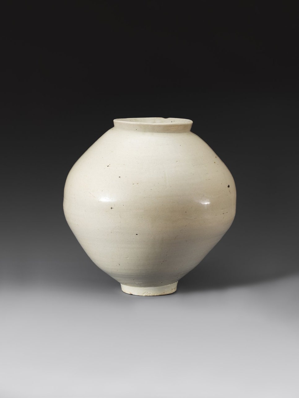 A round Joseon white porcelain moon jar with an undecorated surface and a wide mouth.