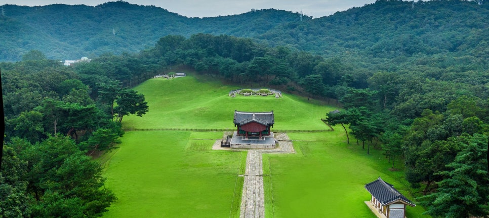 A Joseon royal tomb mound: stone figures lined up on the grass slope leading up to the burial mound