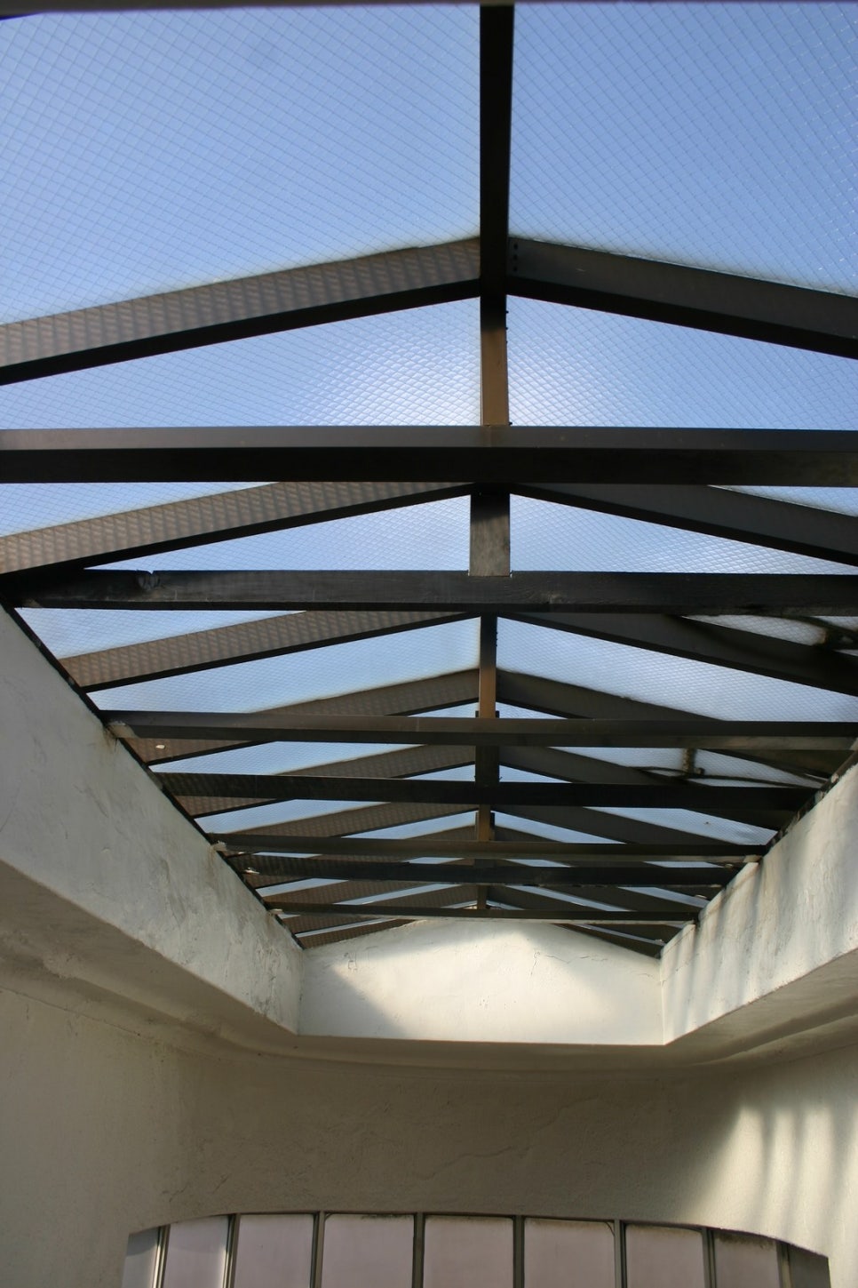 Looking up at the steel frame of the former headquarters' skylight, light coming through the lattice.