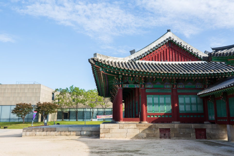 The modern MMCA Seoul building seen layered beyond the tiled eaves of a Jongchinbu hall.