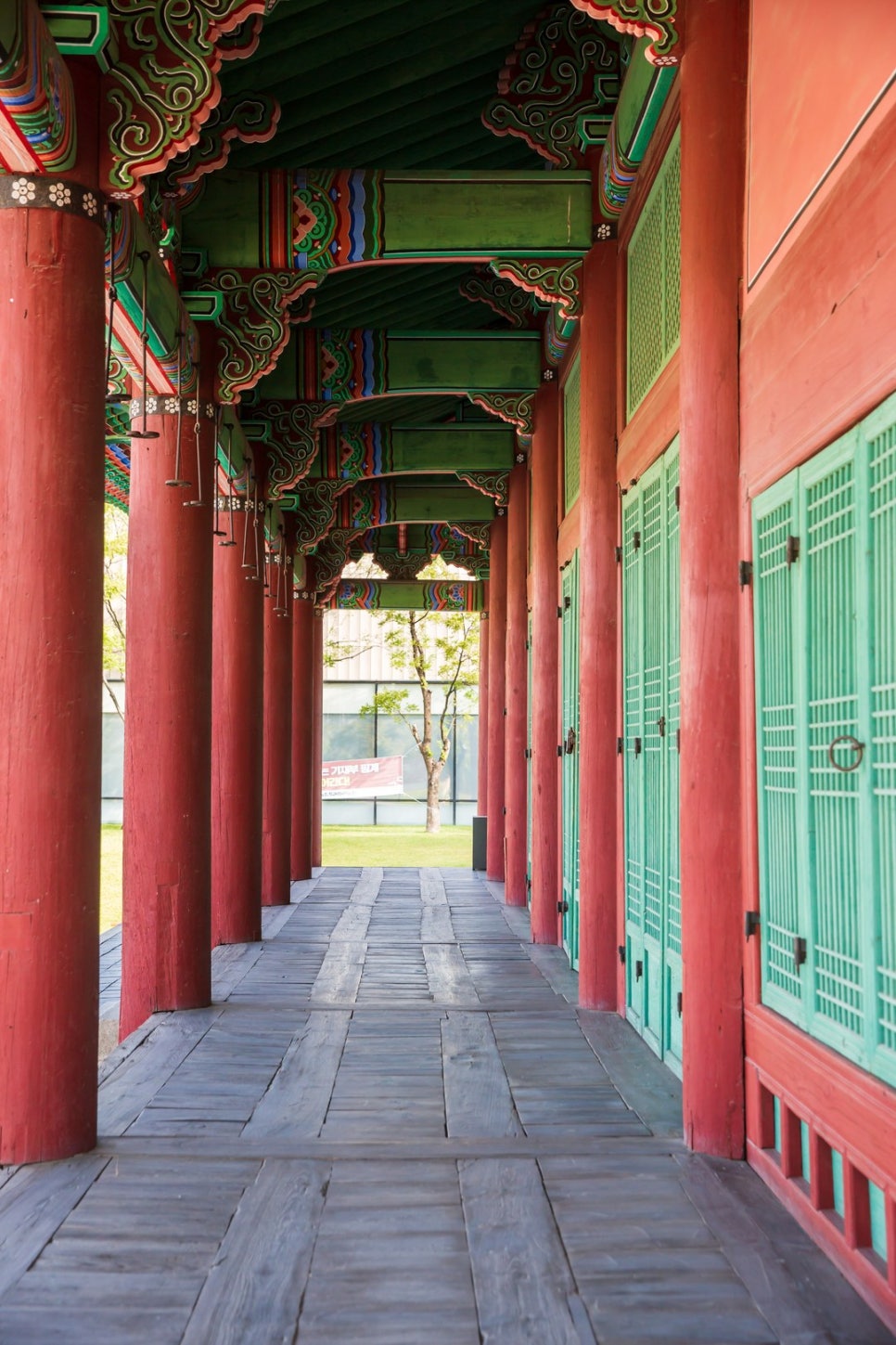 A view along the covered corridor connecting Gyeongeundang and Okcheopdang, columns in a row and the wooden floor running away.