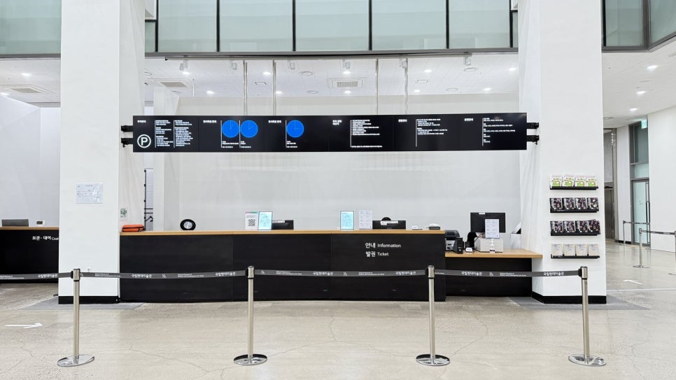 The information and ticket desk on the ground floor of MMCA Cheongju: a black counter, an information display and a barrier post.