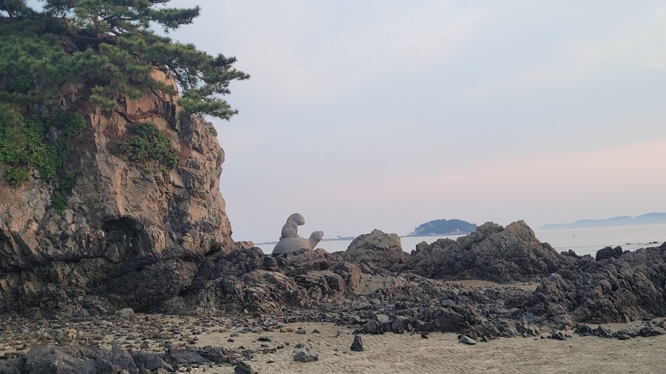 Jarabawi rock and a sculpture of the turtle from the Byeoljubu tale on the mudflat at Cheongpodae beach.