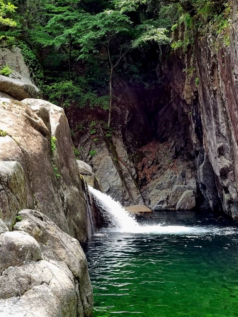 Yongso: water falling through a narrow gap in the rock into a deep blue-green pool.