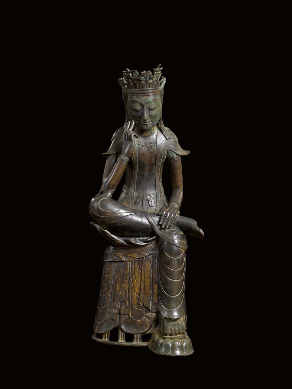 A gilt-bronze bodhisattva seated with one leg over the other knee, fingers against its cheek.