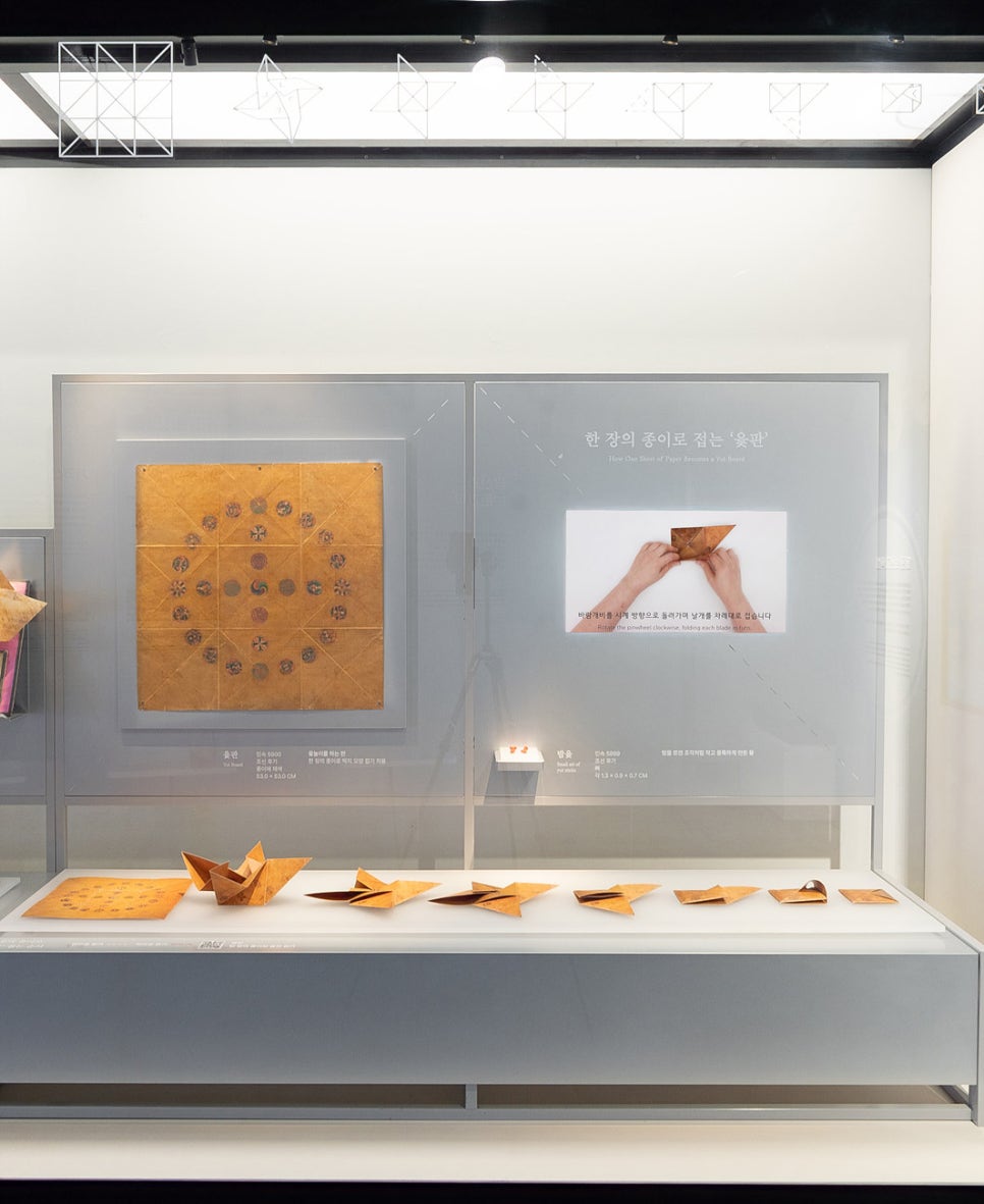 An enlarged image of the board and a video of the folding sequence on the wall, with models of each fold stage lined up on a shelf below