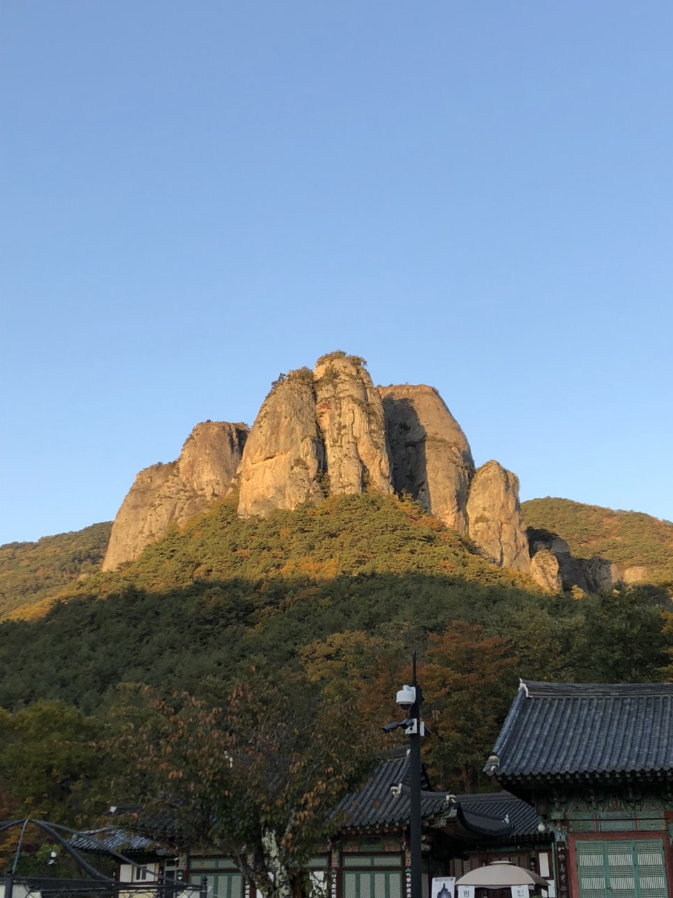 The rock peaks of Juwangsan rising behind the tiled roofs of Daejeonsa temple in autumn colour