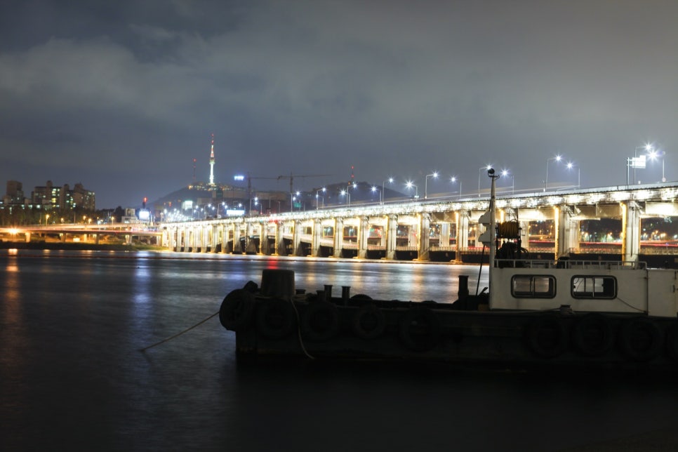 Banpo and Jamsugyo bridges lit up over dark water, with boats moored along the bank