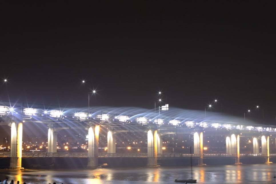 Piers of Banpo Bridge glowing from lights below, lined up across the river at night