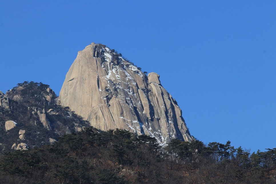 눈 덮인 겨울 북한산 인수봉의 거대한 바위 벽