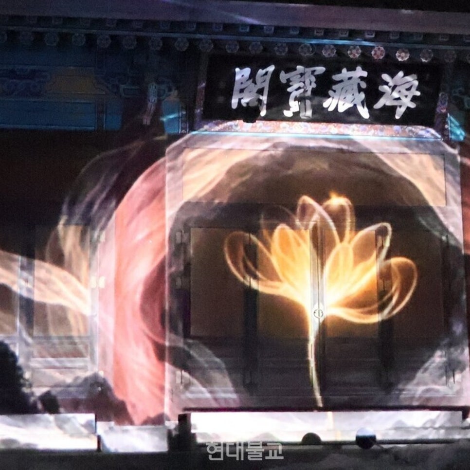 A large lotus of light rising above Haejangbogak hall against a dark sky during the main show