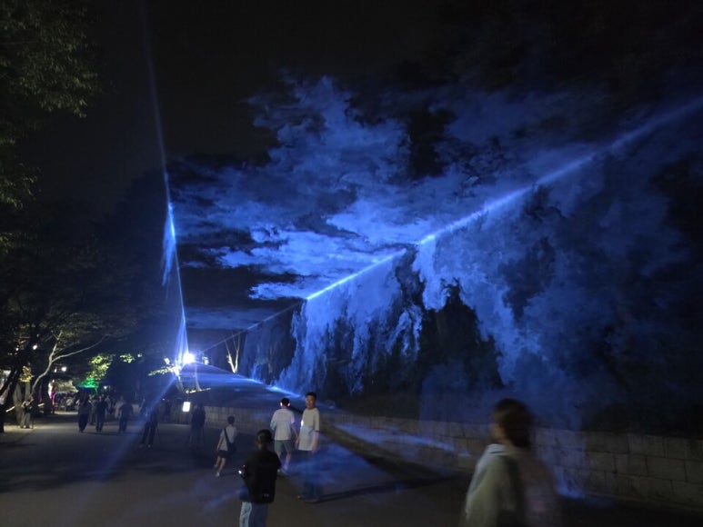 A path at the temple entrance with trees and ground lit up at night