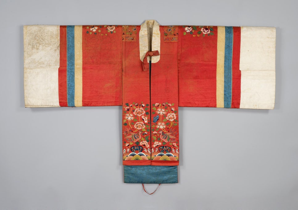 A Joseon-era hwarot wedding robe laid flat, red silk embroidered with flowers, birds and waves
