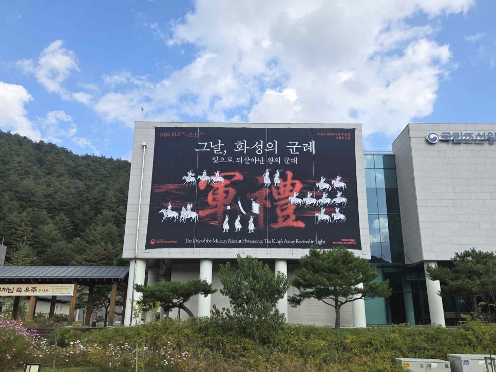 The tiled-roof museum building seen from the front, with a large banner for the exhibition hung across the facade