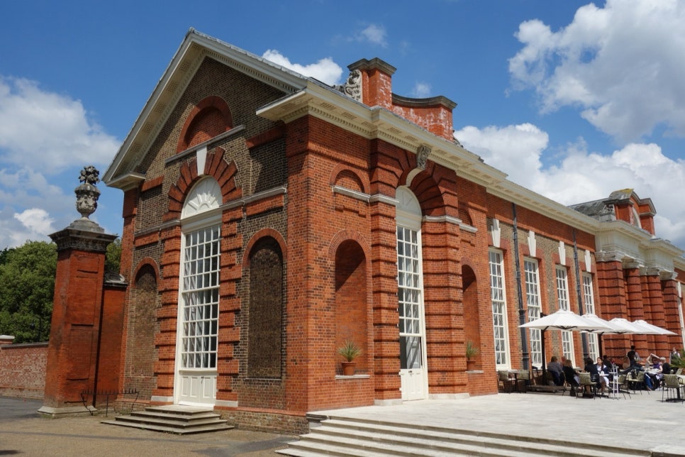 The red-brick orangery at Kensington Palace in London, with a lawn in front