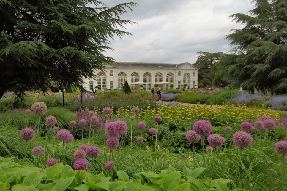 The white stone orangery at Kew with tall arched windows, seen across a lawn