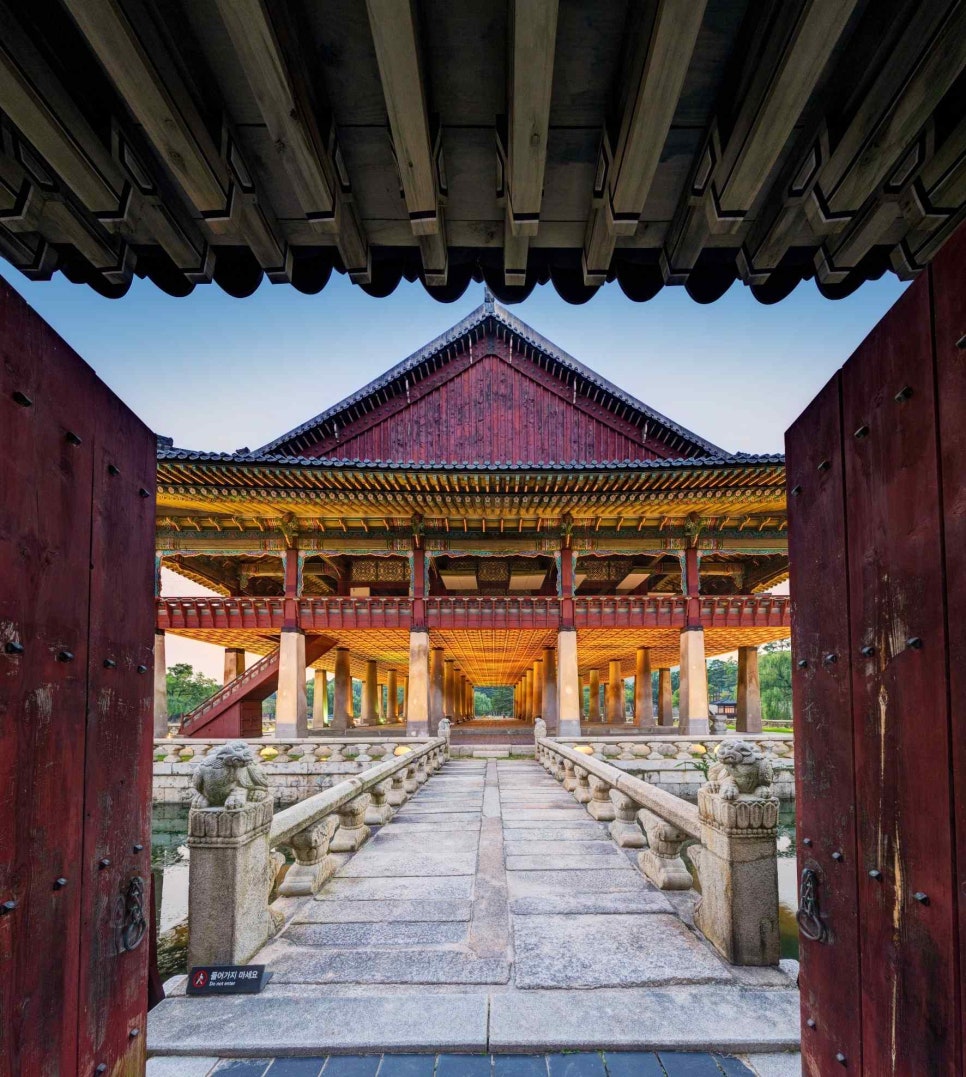 Gyeonghoeru pavilion and its pond at Gyeongbokgung, framed by a dark doorway, with full green summer foliage