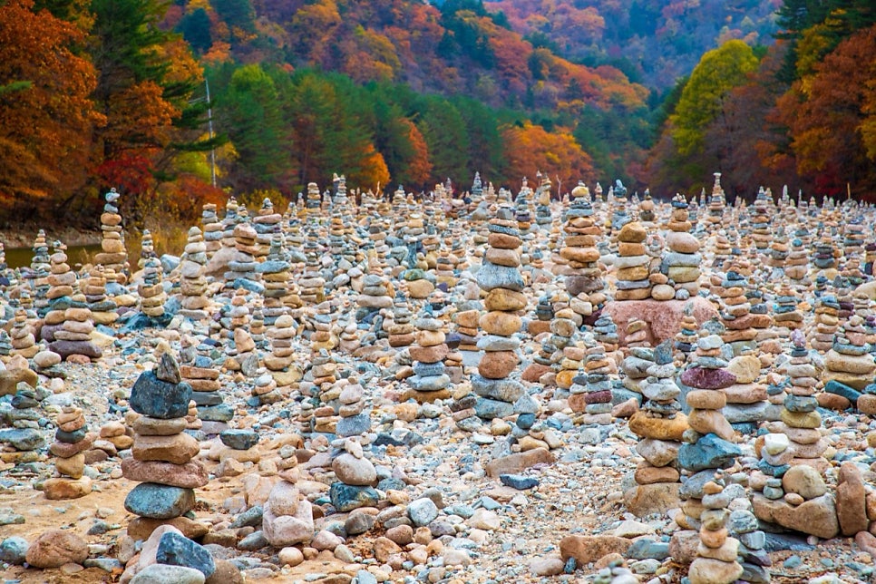 Dozens of small stone cairns stacked on the gravel bed of Baekdam Valley