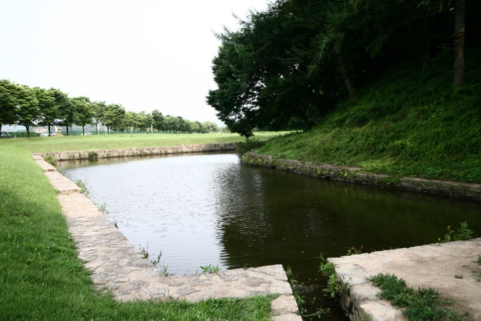 The water-filled Wolseong moat along a grassy embankment in Gyeongju, in daylight