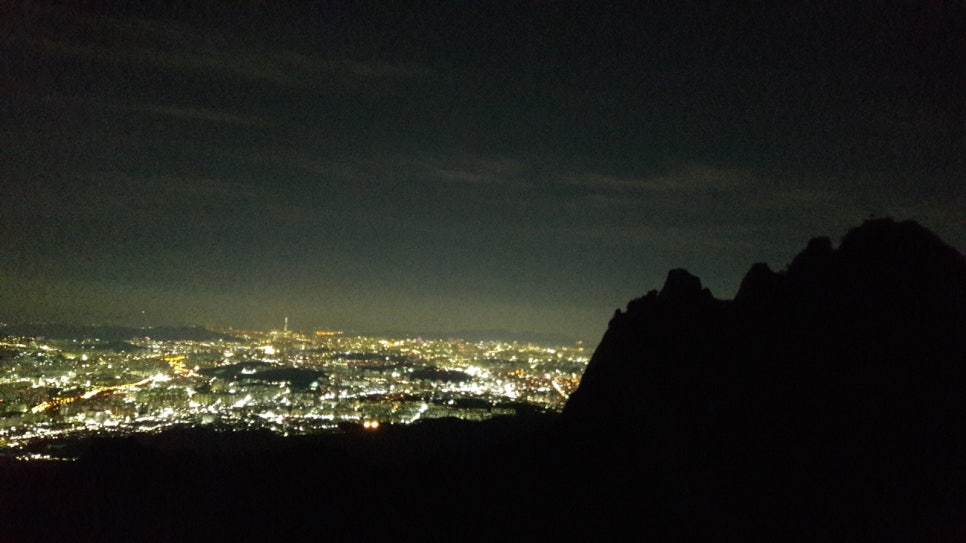 The rocky Jaunbong ridge of Dobongsan with the lights of Seoul spread out beyond it at night