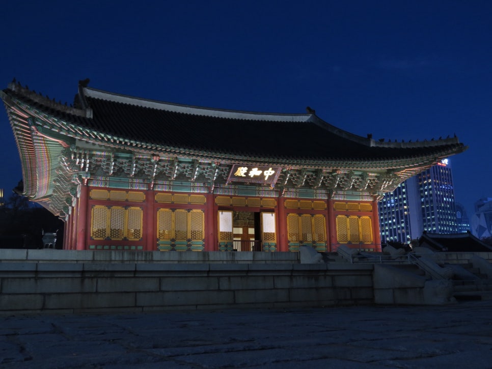 Junghwajeon at Deoksugung seen from the front at night, with lit office towers behind