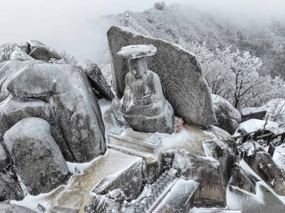 The snow-covered seated stone Buddha of Gwanbong (Gatbawi) on Palgongsan with the rocks around it